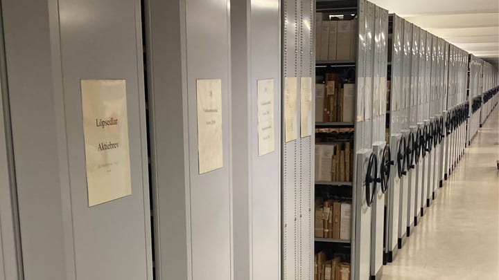 Kompaktarkiv i magasin – gång med handhjul (wide) Rullarkiv med handhjul och etiketter – lång gång i arkivmagasin